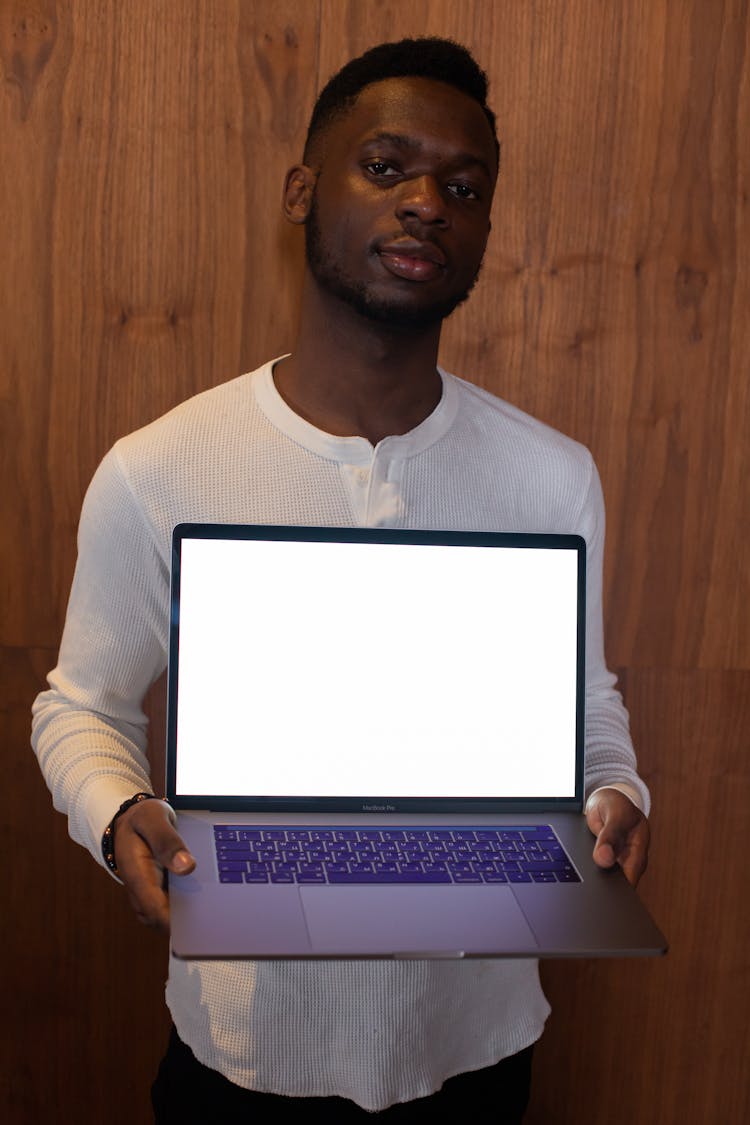 Man Holding A Laptop Displaying A Blank White Screen 