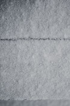 Detailed view of snow-covered roof tiles creating a winter pattern and texture.