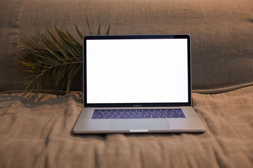 Free A laptop with a blank screen sitting on a comfortable sofa, ideal for design and technology themes. Stock Photo