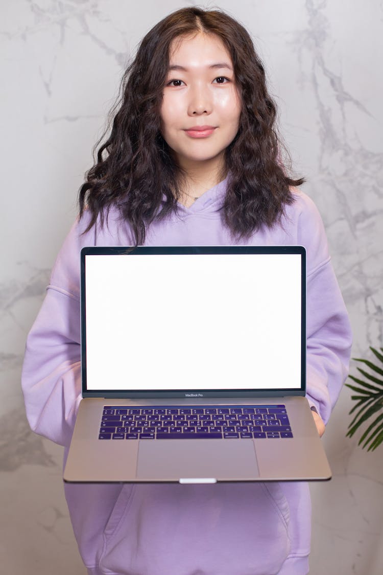 Woman Holding A Laptop Displaying A Blank White Screen 