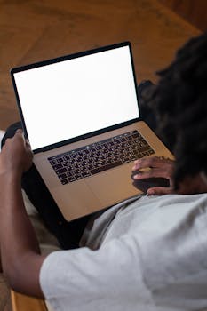 African American man using a laptop with blank screen indoors.