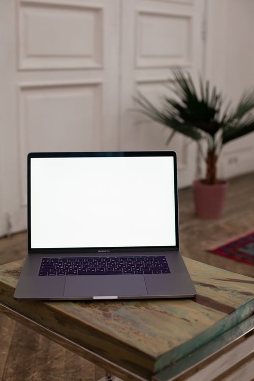 Free Open laptop with blank screen on a wooden table in a stylish interior setting. Stock Photo