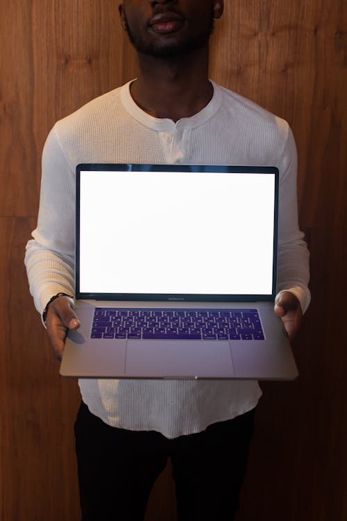 Man Holding a Laptop Displaying a Blank White Screen