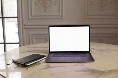 Free Laptop with blank screen on a luxurious marble table in a stylish interior setting. Stock Photo