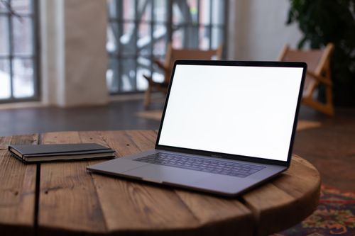 Free A sleek laptop on a wooden table with an open blank screen, perfect for mockup use in modern interiors. Stock Photo