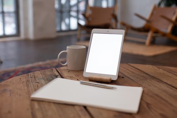 A tablet and a mug of coffee on a wooden table, ready for morning reading — photo by KATRIN BOLOVTSOVA on Pexels