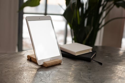 Elegant tablet on a wooden stand beside closed notebooks, perfect for productivity and organization themes.