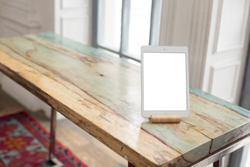 A Tablet with a Blank Screen on a Wooden Table