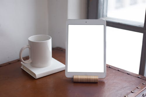 A White Ceramic Cup Beside the Tablet