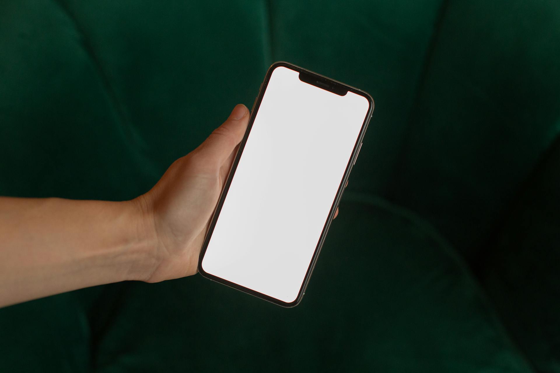 A close-up of a hand holding a smartphone with a blank white screen, ideal for digital mockups.