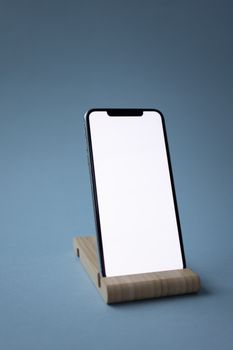 Minimalist shot of a smartphone with a blank screen on a wooden stand.