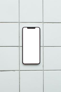 A smartphone with a blank screen positioned on a tiled surface, ideal for mockups.