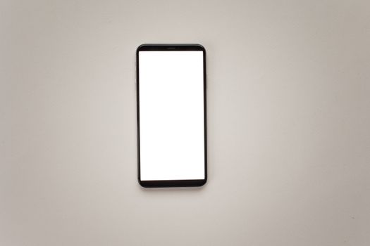 Top view of a smartphone with a blank screen for mockup design on a neutral background.