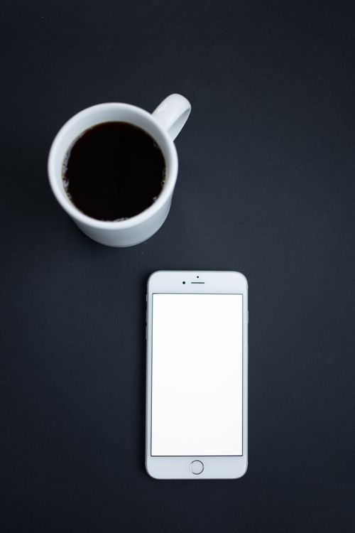 Free Top view of a coffee cup and smartphone on dark surface, perfect for technology and lifestyle themes. Stock Photo