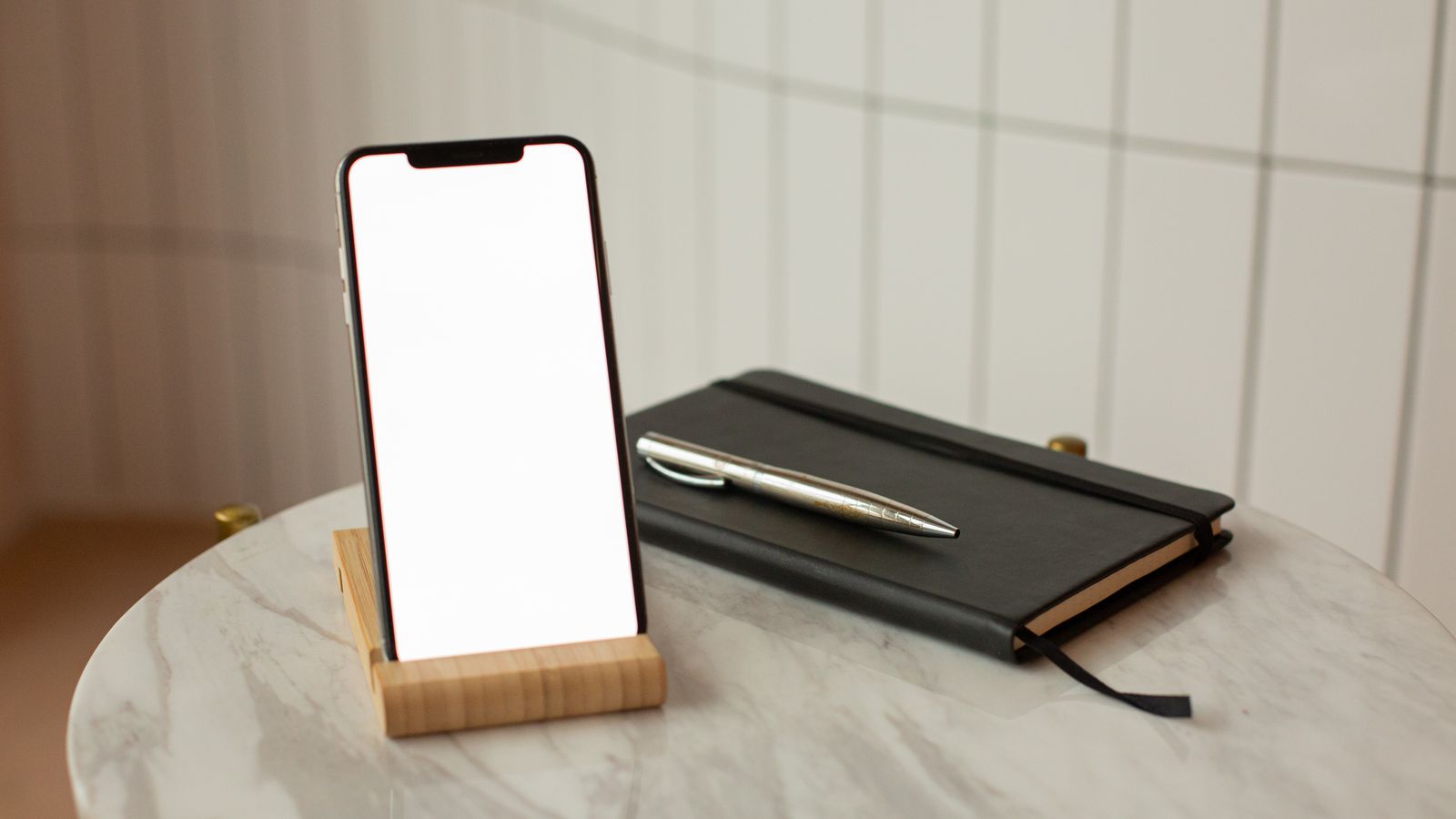 A blank-screen phone beside a closed notebook and pen