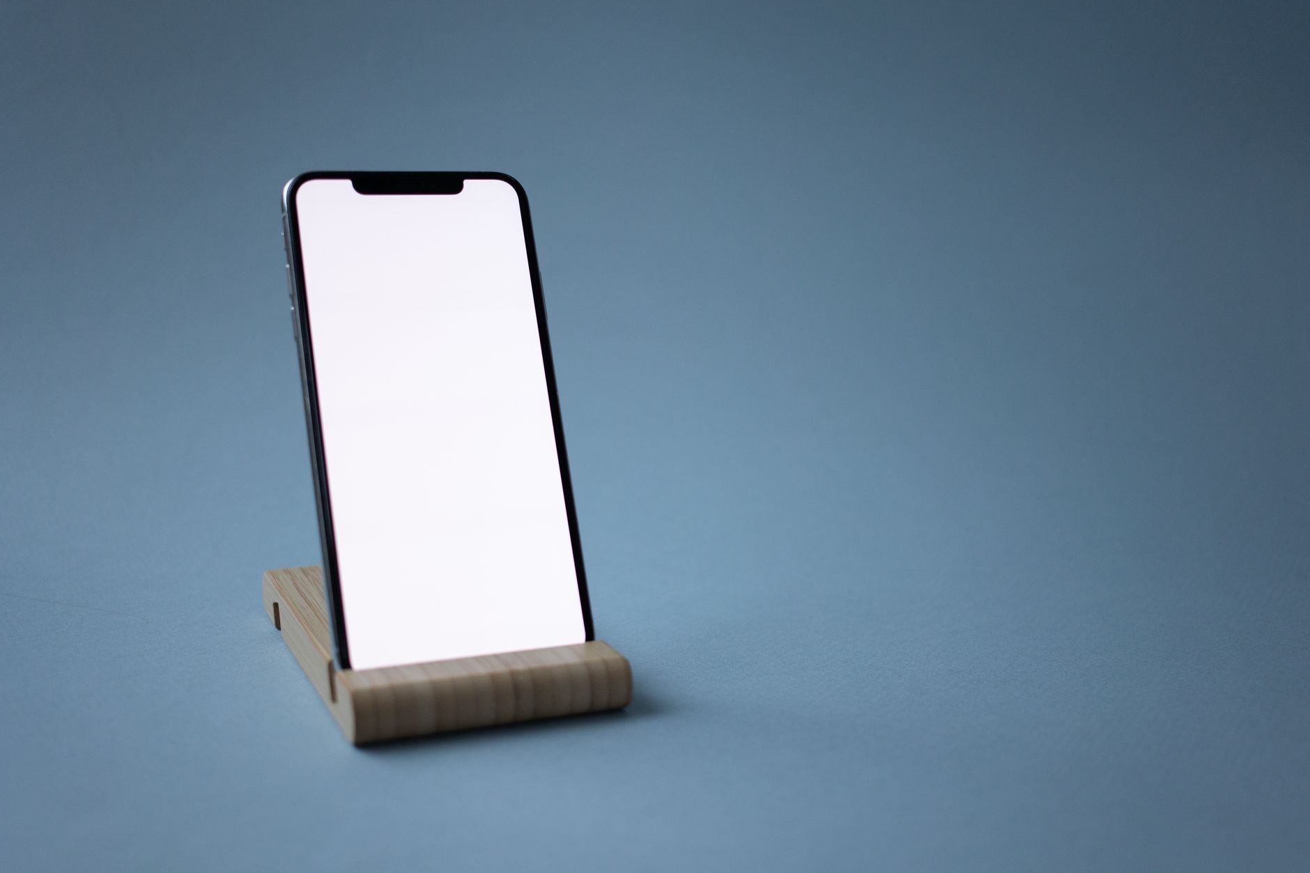 A sleek smartphone set on a minimalist wooden stand against a plain backdrop, perfect for tech displays.