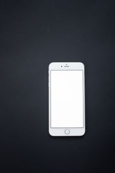 Simple white smartphone on dark surface, perfect for design mockups or tech adverts.