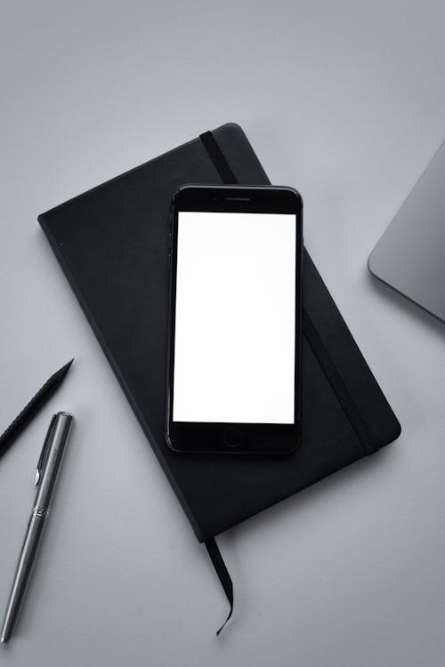 Free A Black Smartphone with Blank Screen on a Black Notebook
 Stock Photo