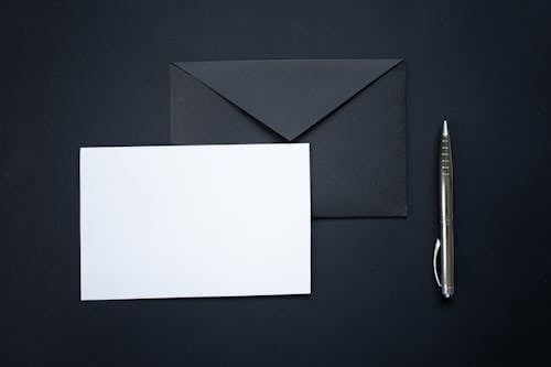 A Piece of Blank Paper on a Black Envelope Beside a Silver Ball Pen