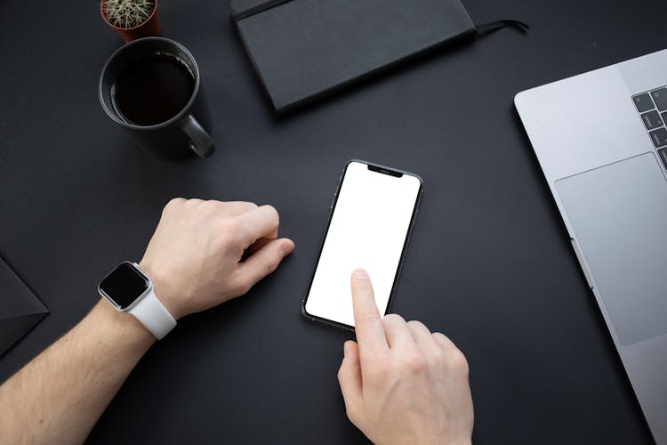 A Person Wearing A Smartwatch Touching The Blank Screen Of A Smartphone 