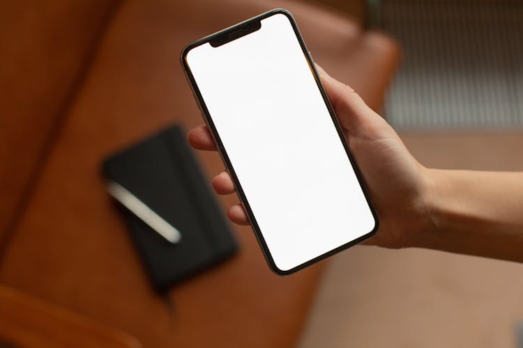 A Person Holding A Smartphone With A Blank Screen
