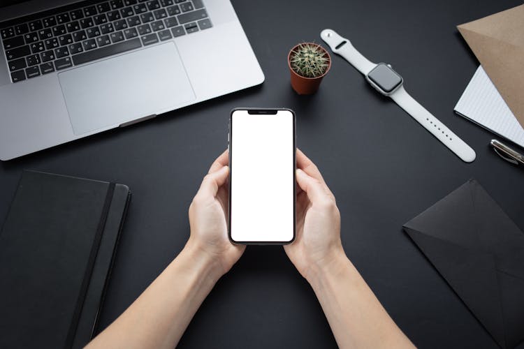 A Person Holding A Smartphone With A Blank Screen
