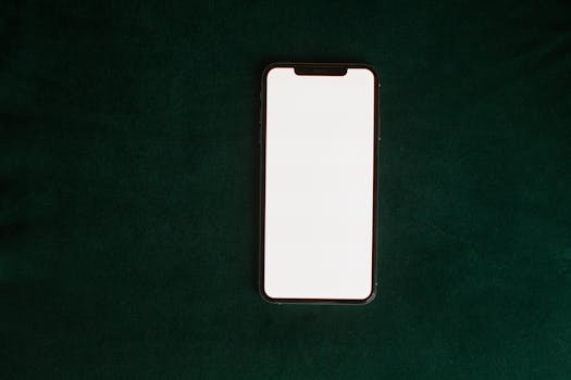 Top view of a smartphone with a blank screen on a green background, perfect for mockups.