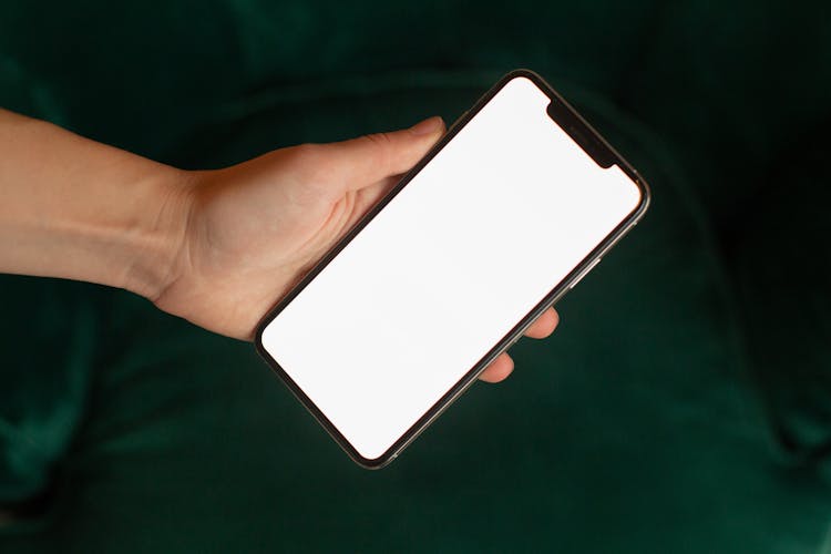 A Person Holding A Smartphone With A Blank Screen
