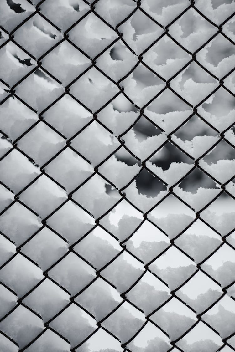 A Black Metal Chain Link Fence Covered With Snow