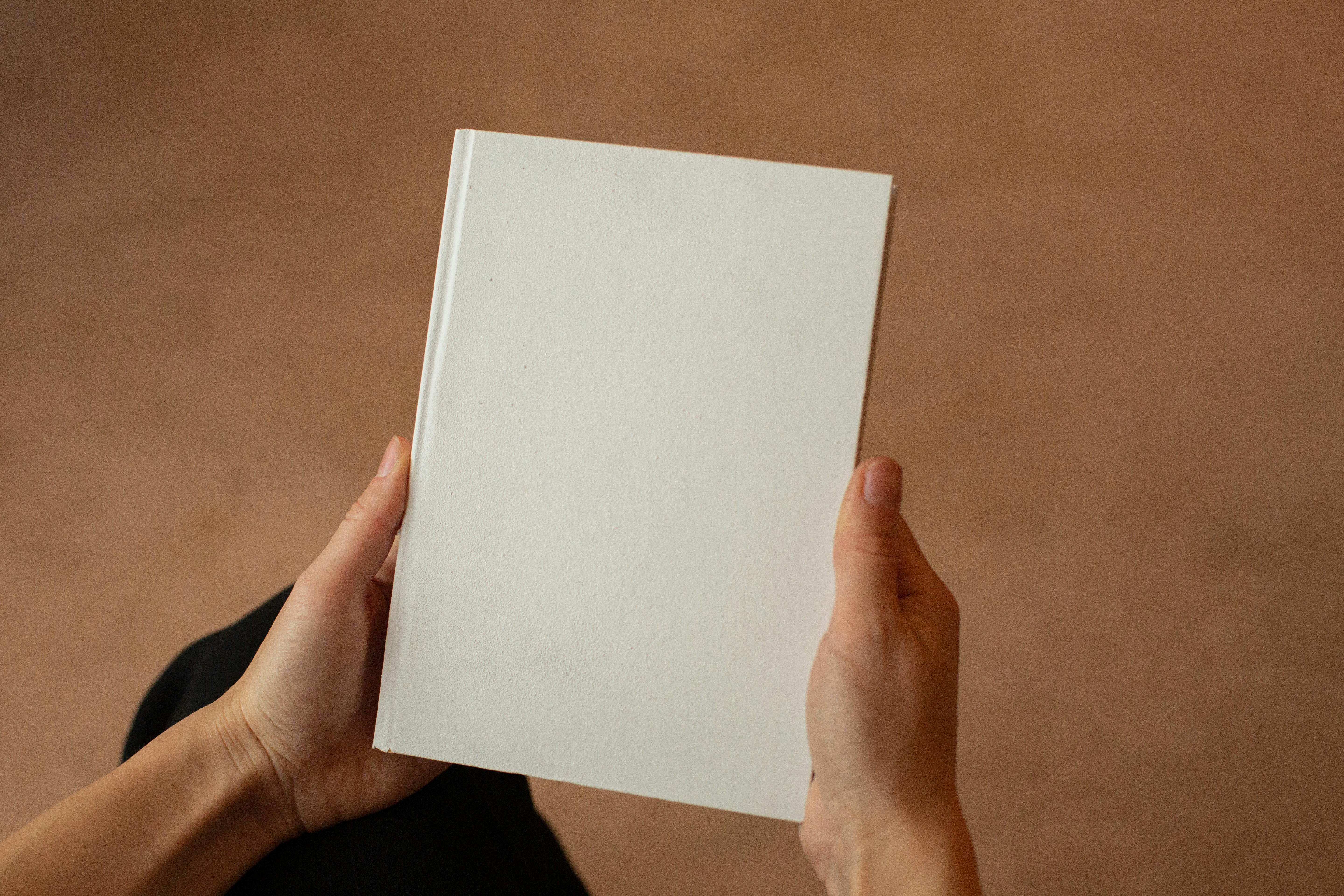 person holding hardcover book with blank cover