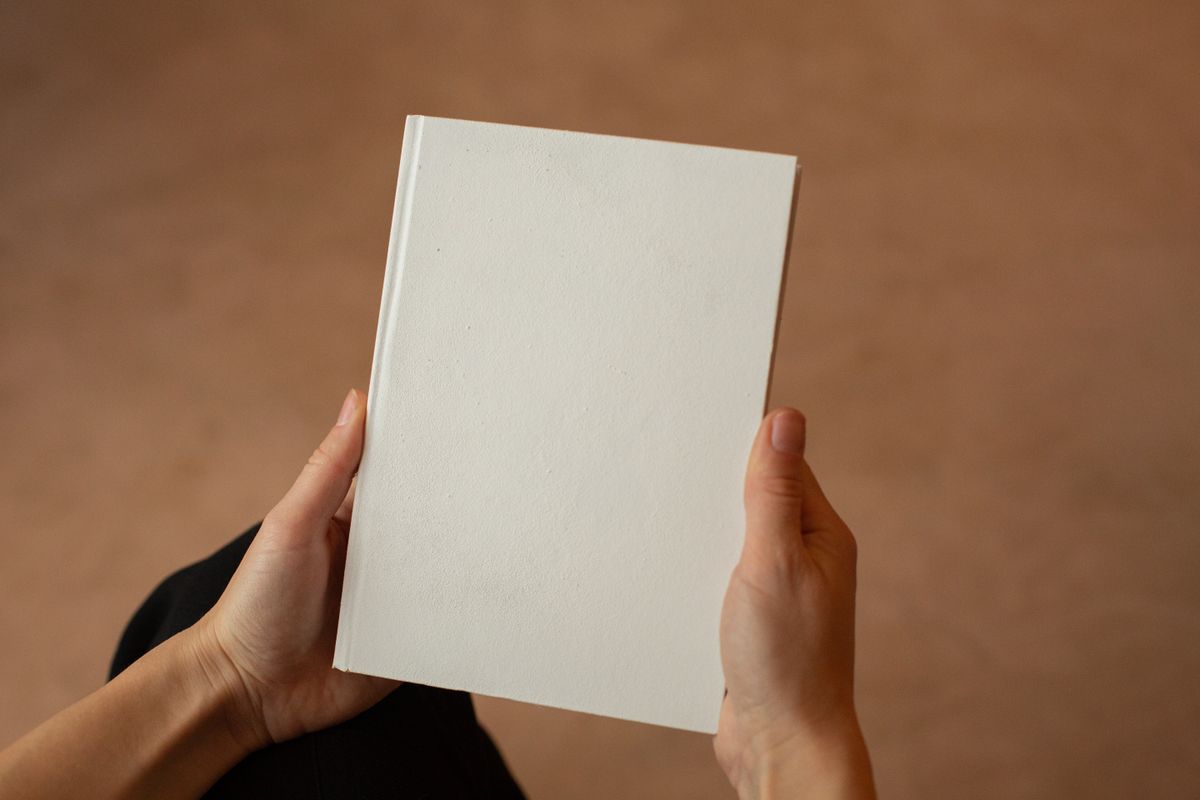 A linen-bound hardcover held in two hands