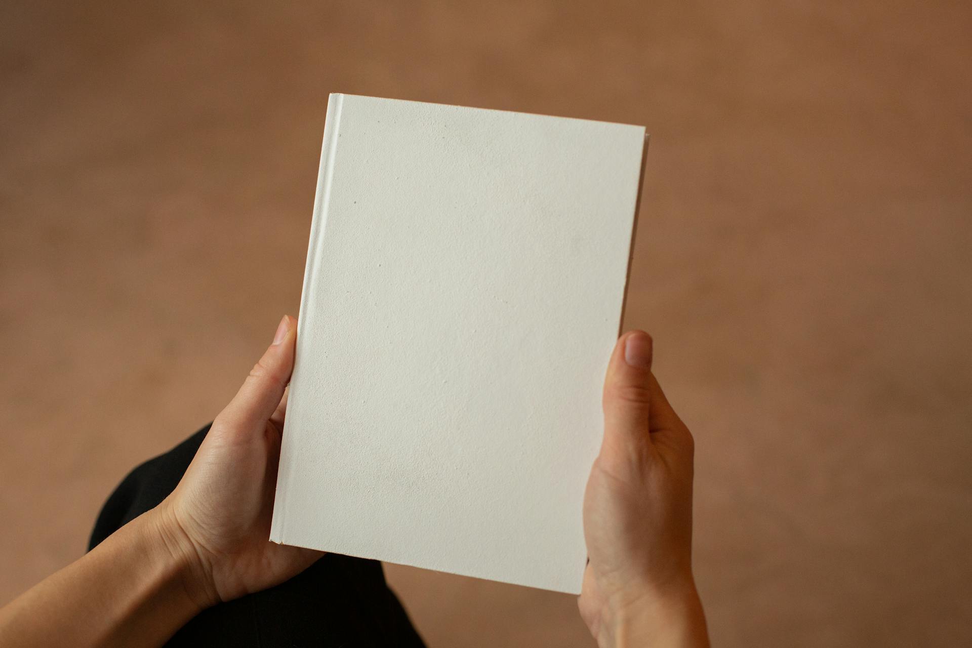 Person holding hardcover book with blank cover