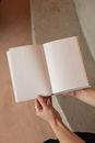 From above of unrecognizable female holding book with blank pages while sitting near stone stairs