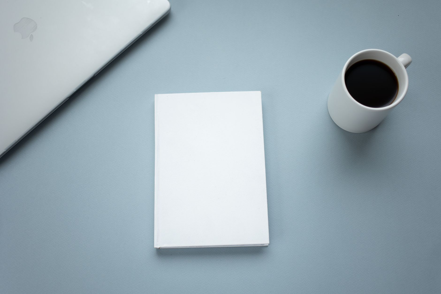 A clear desk with an open planner, a pen and a coffee mug