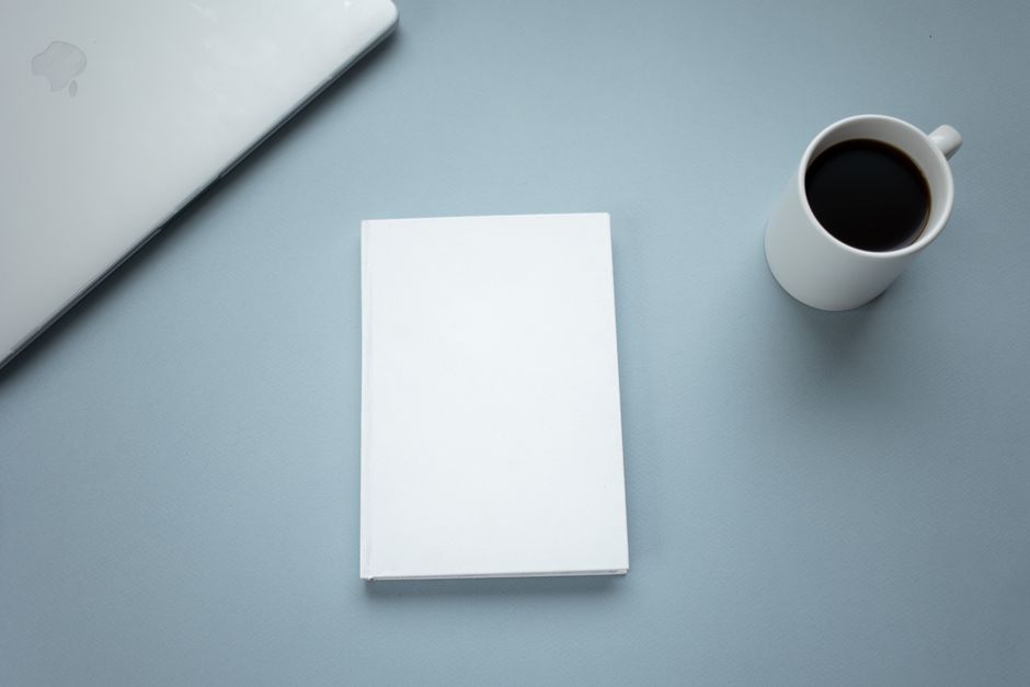 I Don't Want to Write My Essay: A Guide for Stuck Students 2 Top view of closed laptop placed near mug of hot americano and white hardcover book on table
