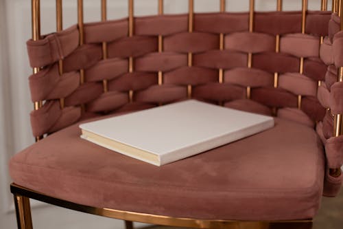 White hardcovered book placed on brown armchair