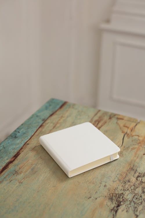 From above of blank hardcover of notebook placed on shabby wooden desk in light apartment