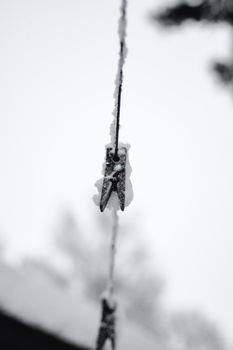 Monochrome photo of a snow-covered clothesline with a pin in winter Estonia.