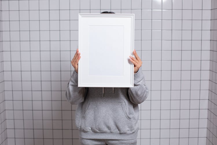 Faceless Person Covering Face With Empty Photo Frame