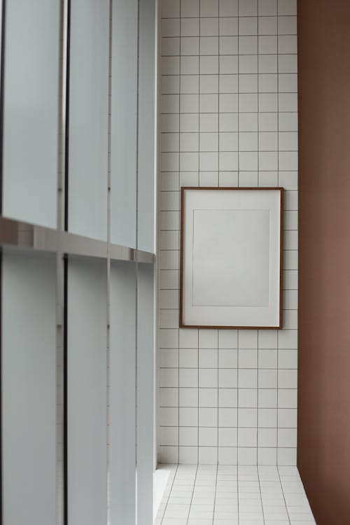 Empty photo frame hanging on tiled wall in corridor