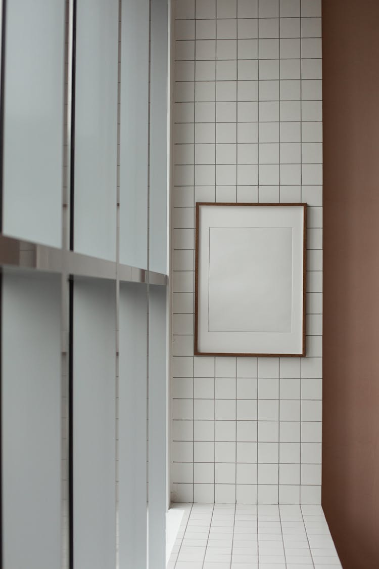 Empty Photo Frame Hanging On Tiled Wall In Corridor