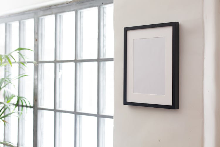 Simple White Frame Hanging Near Windows And Green Potted Plant