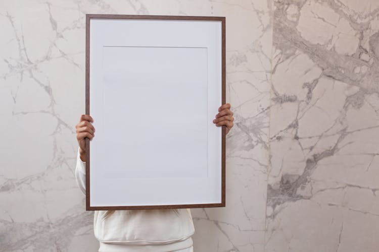 Person Showing Large Blank Frame Near Wall With Patterns