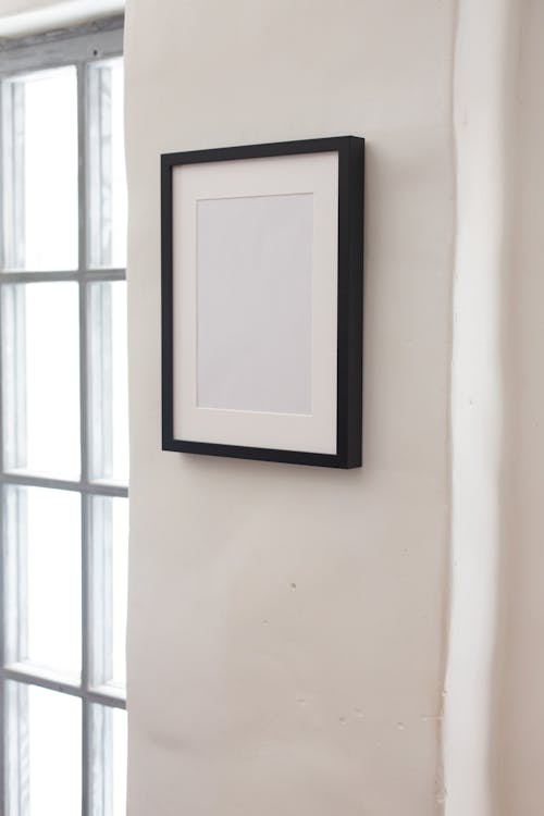 White frame hanging on wall between windows