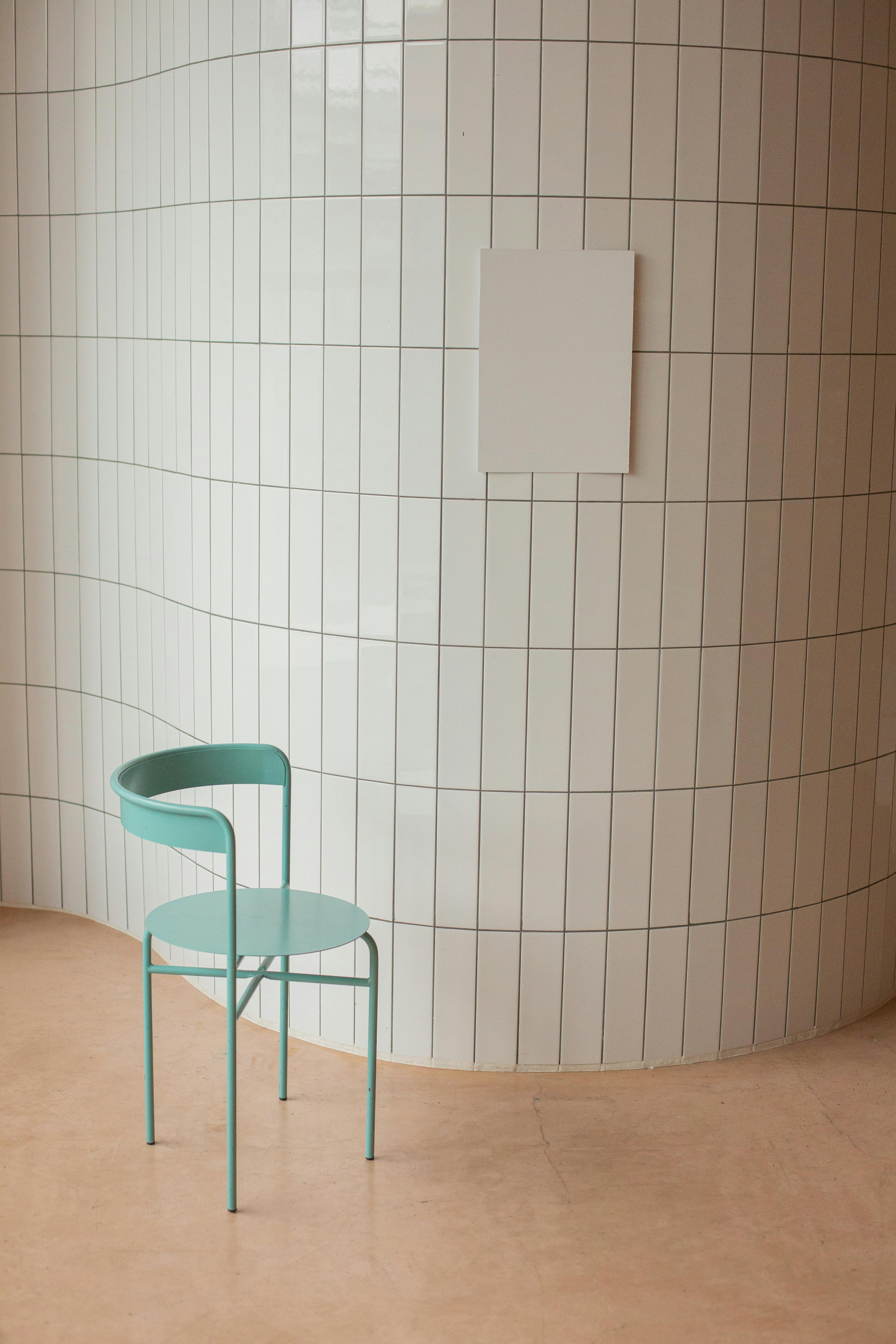 chair near wall with ceramic tile and white placard