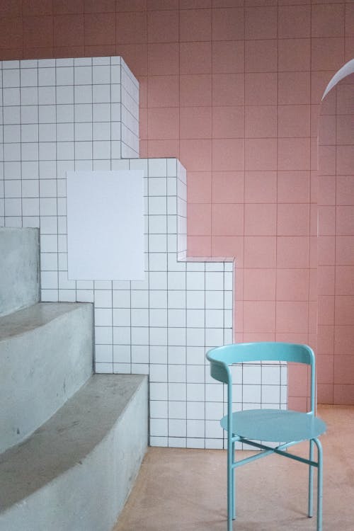 Interior of modern room with minimalistic metal chair and empty white canvas hanging on geometric tile walls