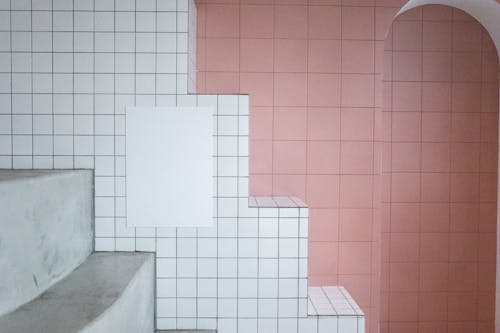 White blank paint hanging on tile white wall near arched entrance in room with minimalistic design