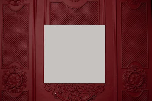 White square board placed on red wall with ornamental elements in bright room