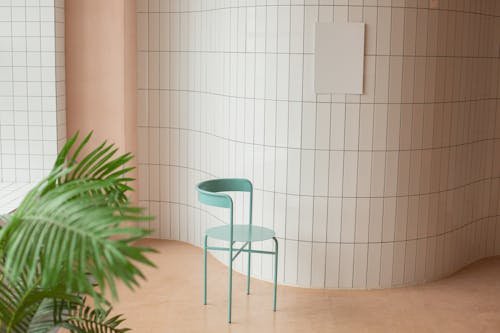 Empty bright room with white canvas placed on tile wall near chair and green potted plant