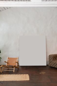 White mock up poster with copy space at wall in light furnished room with armchair and couch in modern studio